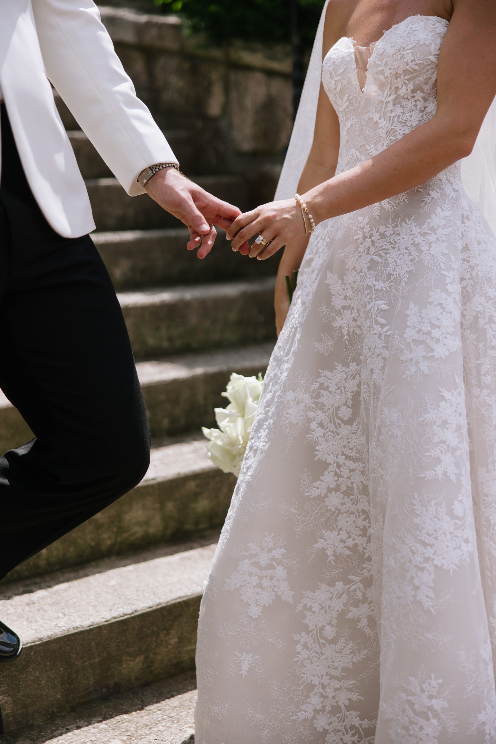 Bride and groom holding hands on stone steps — Mrs. Sugar Booger wedding, Highlands NC